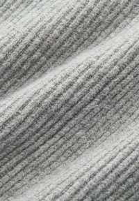 Nahaufnahme von weichem, hellgrauem, geripptem Strickstoff mit einem strukturierten Muster aus vertikalen Linien und gestrickten Schlaufen.