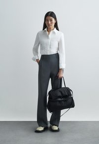 Λευκό πουκάμισο, γκρι παντελόνι ψηλής μέσης, μαύρη τσάντα puffer, μπεζ παπούτσια, κομψός σχεδιασμός, απαλές υφές, μινιμαλιστικό στυλ.