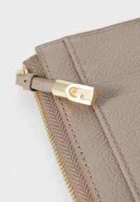 Grijze gestructureerde portemonnee met een glad leren accent, gouden ritsbeslag en een metallic sluiting. Bevat meerdere kaartsleuven.