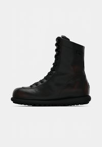 Černá kožená bota s vysokým svrškem, kulatou špičkou a pryžovou podrážkou. Má zapínání na knoflíky a hladký povrch s jemným leskem.