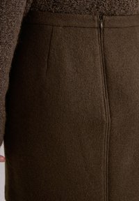 Brąskowa spódnica z mieszanki wełny o gładkiej teksturze, z centralnym szwem i zapięciem na zamek z tyłu. Prosty, dopasowany krój.