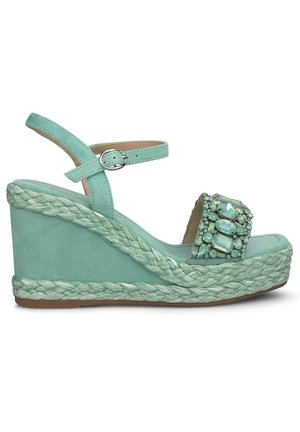 Sandalo con zeppa in suede aqua e suola in juta intrecciata, dotato di una cinghia decorata con gioielli e di una fibbia regolabile alla caviglia.
