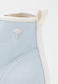 Light blue canvas ankle boot with white rubber accents and stitching; features a small white emblem on the side.