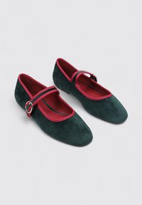 Bailarinas de ante verde con ribete y correa rojos, diseño de punta afilada y detalle de hebilla plateada redonda.