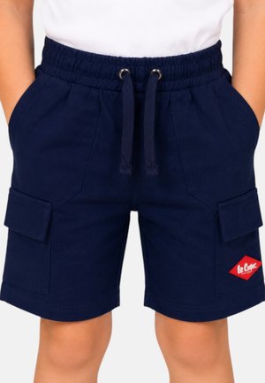 Enfant portant un short cargo bleu marine à taille à cordon, poches avant et écusson rouge Lee Cooper, mains dans les poches.