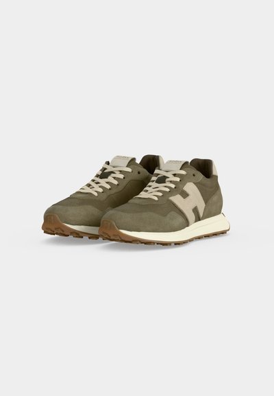 Paire de baskets en daim vert olive avec lacets beiges et logo "H" sur le côté, semelle intermédiaire blanche et semelle extérieure en caoutchouc marron sur fond blanc.
