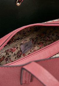 Różowa syntetyczna torebka wewnątrz z podszewką w kwiatowy wzór, zamykaną kieszonką oraz metką Anna Field. Czarny zewnętrzny wygląd z złotymi elementami.