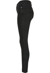 Jeans skinny negros con una textura de denim suave, con una cintura de media altura, cinco bolsillos y detalles de costura estándar.