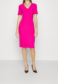 Aangepaste roze jurk met korte mouwen, V-hals, kniehoogte, gemaakt van soepele stof, met zijnaaddetails en een gestroomlijnde silhouet.