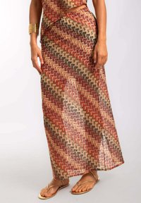 Falda maxi con un patrón geométrico en rojo, marrón y beige, hecha de una tela transparente con una textura suave y detalle de apertura lateral.