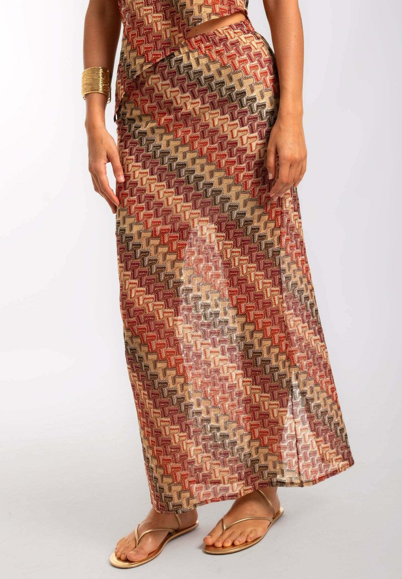 Falda maxi con un patrón geométrico en rojo, marrón y beige, hecha de una tela transparente con una textura suave y detalle de apertura lateral.