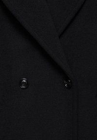 Cappotto in lana nera con design doppiopetto, rever a punta e due bottoni neri. Tessuto liscio con dettagli minimi.