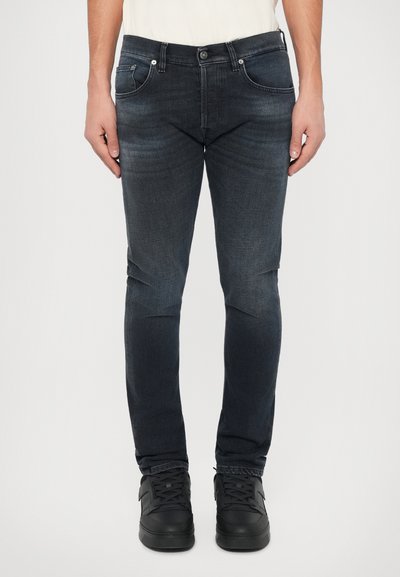 Jean en denim bleu foncé à coupe slim, doté de cinq poches, de quincaillerie en métal et d'un léger délavage. Assortis avec des baskets noires.