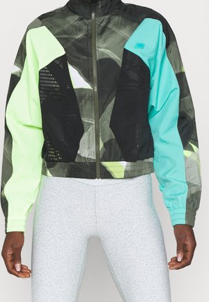 Cropped zip-up jacket with black mesh and multicolor panels in neon green, teal, and dark camouflage, worn with light gray leopard-print leggings.