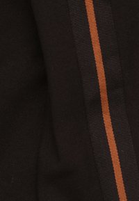 Tissu noir avec une texture lisse, arborant une bande verticale orange. La bande est composée d'un matériau côtelé, ajoutant un élément de contraste.