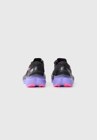 Une paire de chaussures de course noires avec des semelles violettes et des accents roses, vues de l'arrière sur un fond blanc.