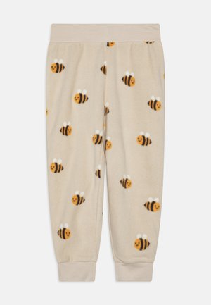 Beige flīsa pidžamu bikses ar smaidošu bišu rakstu, kurām ir melnas svītras un baltas spārni. Elastīga jostasvieta un tievas piedurknes.