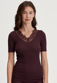 Bordeaux kortemouwtop met een ribbelstructuur en een V-halslijn met kanten rand. Het aansluitende ontwerp accentueert de silhouet.