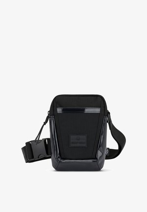 Černá crossbody taška s texturovaným předním dílem a lesklými patentovanými detaily. Obsahuje nastavitelný popruh a logo nášivku vpředu. Obdélníkový tvar.