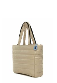 Beige puffer kott, millel on tikitud disain, mustad rihmad ja sinine silt. Omab läikivat tekstuuri ja ristküliku kujundit.