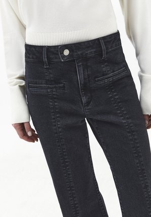 Donkere denim jeans met een hoge taille, voorzien van zakken aan de voorkant en een knoopsluiting met marmerprint. Gemaakt in combinatie met een lichtgekleurde, geribbelde trui.