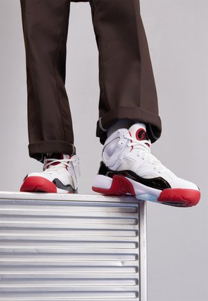 Baltas un melns sporta apavi ar sarkaniem akcentiem. Satur tīkla un ādas materiālus, noapaļots purngals un teksturēta gumijas zole.