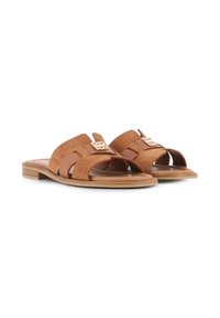 Sandalias deslizantes de ante marrón con dos correas anchas, una pequeña hebilla decorativa y una suela de madera de perfil bajo. Diseño texturizado y abierto en la parte delantera.
