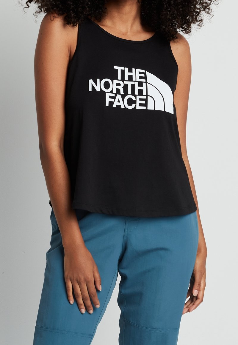 Camiseta sin mangas negra con un escote redondeado que presenta el logo blanco "THE NORTH FACE" en la parte frontal. Material de algodón, corte relajado.