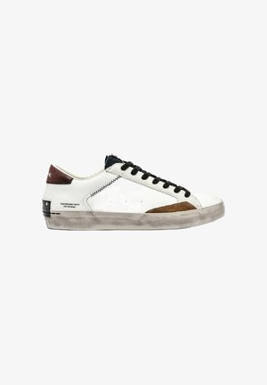 Sneaker bianco con lacci neri, accento in suede marrone, suola grigia testurizzata, presenta dettagli di cucitura e un'etichetta con il marchio sul tallone.