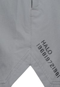 Ljust grå shorts med en slät textur, prydda med en svart tryckt "HALO 196819721981" detalj och en sned söm vid fållen.
