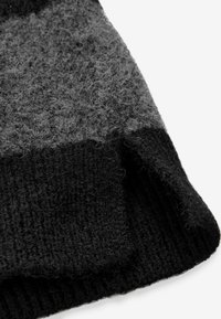 Struktureret uldhat i nuancer af grå og sort, med et ribstrikdesign og en blød, fuzzet finish. Glatte kanter og alsidig stil.