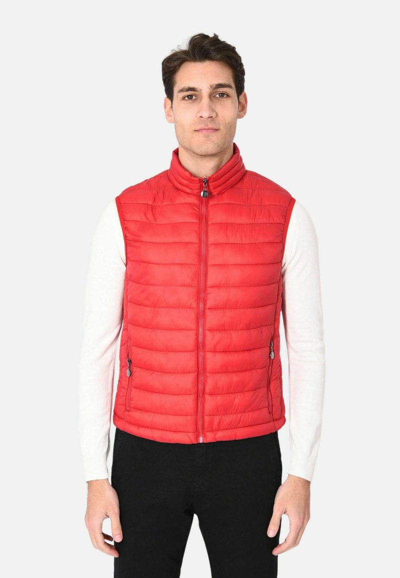 Gilet isolato rosso con motivo a righe verticali, colletto alto, zip frontale e due tasche laterali. Indossato sopra una camicia bianca a maniche lunghe.