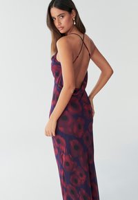 Fialové maxi šaty s květinovým vzorem, vzor červených máků, nastavitelné tenké ramínka a otevřený zadní díl. Hladká, lehká látka.