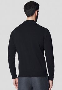 Czarny sweter z dzianiny o okrągłym dekolcie i długich rękawach, z ribbowanym wykończeniem u dołu i na rękawach. Gładka faktura i minimalistyczny design.