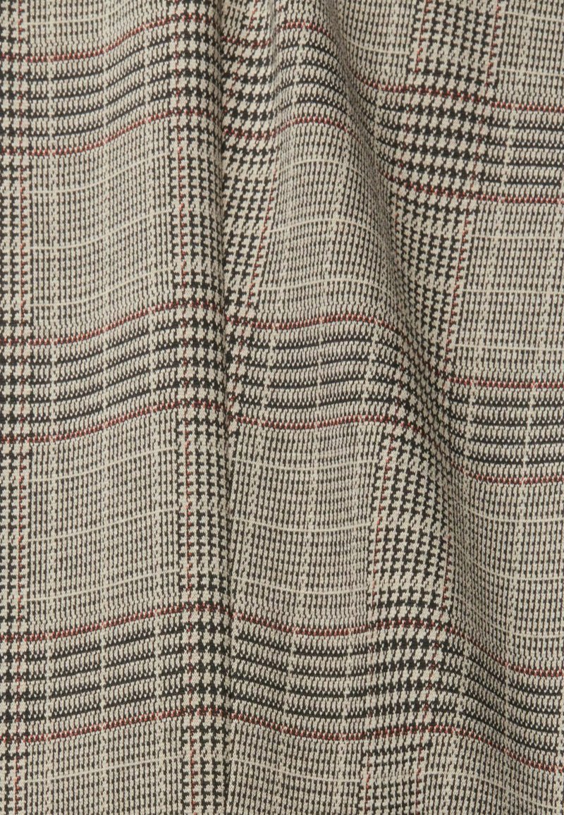 Gewebter Stoff mit strukturierter Oberfläche in neutralen Tönen; zeigt ein kariertes Muster in Schwarz, Weiß und roten Akzenten.