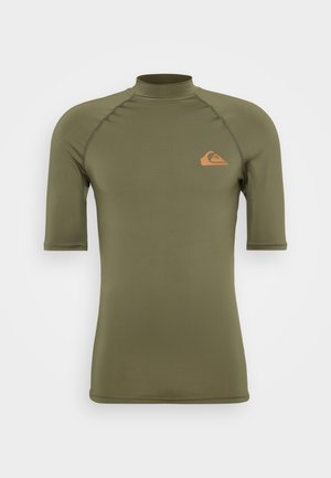 Lyhythihainen rash guard oliivinvihreänä, korkealla kaulalla, valmistettu sileästä ja joustavasta materiaalista, jossa on pieni oranssi logo rinnassa.