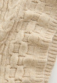 Beigem Strickstoff mit einem strukturierten Kabelmuster. Verfügt über erhabene Quadrate und gerippte Kanten, die Weichheit und Wärme ausstrahlen.