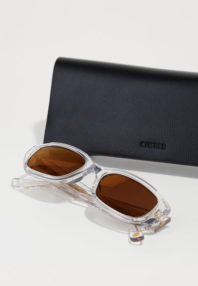 Sunglasses with clear plastic frame and brown lenses. Rectangular shape, featuring gold hardware accents. Accompanied by a black leather case.