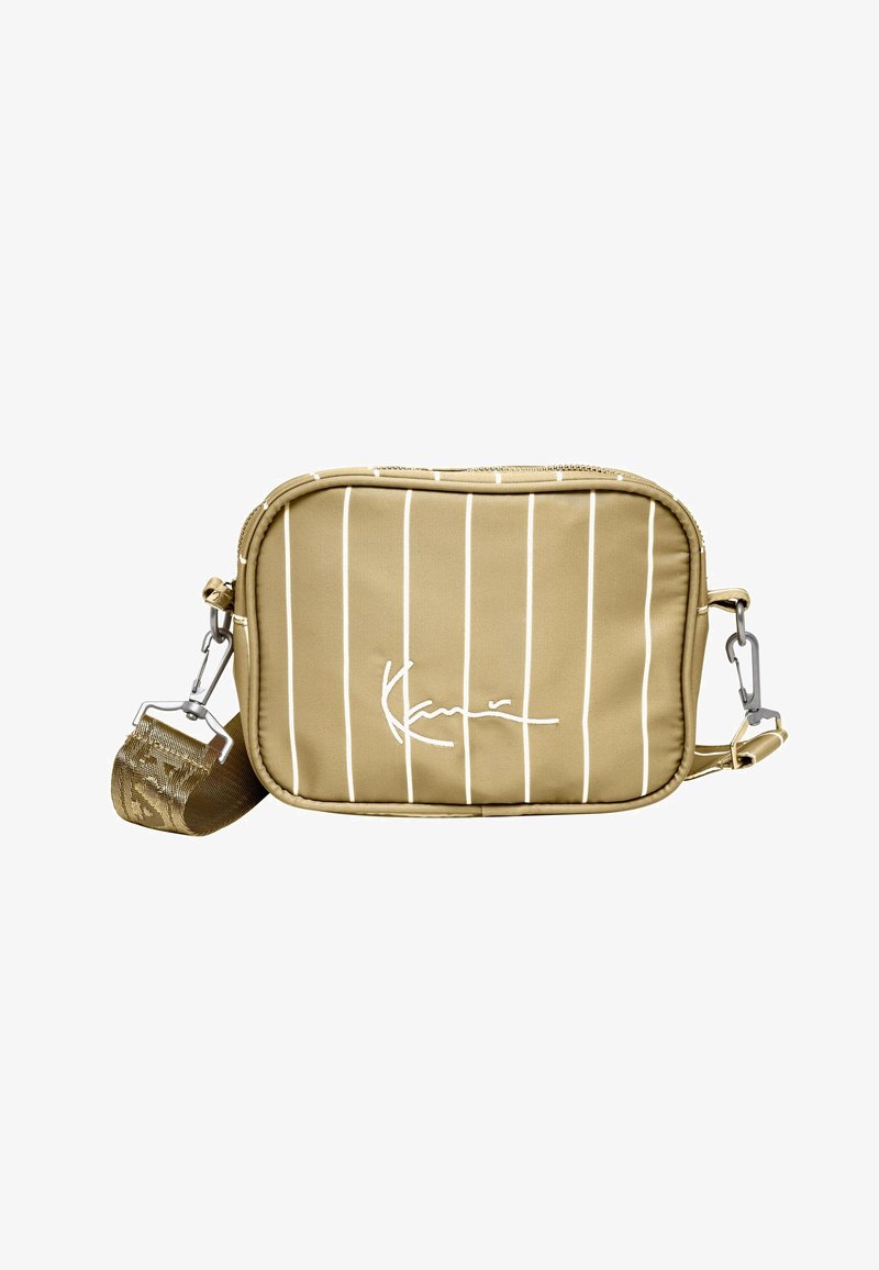 Khaki crossbody-väska med vita vertikala ränder, dragkedjestängning, justerbar rem och metallbeslag; har en signaturlogo.
