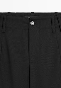 Zwarte op maat gemaakte broeken met een gladde textuur, voorzien van een knoopsluiting, riemlussen en zijzakken. Strakke lijnen en een minimalistisch ontwerp.