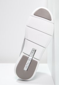 Szary i biały spódnik do sportowego obuwia z teksturowanej szarej gumy, zawiera metaliczny srebrny akcent z brandingiem "MICHAEL KORS". Okrągły kształt pięty.