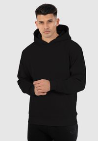 Sudadera negra con bolsillo canguro frontal y puños acanalados, con un diseño sencillo y una textura de tela suave.