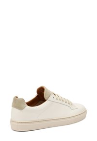 Sneakers bianchi in pelle con tallone e linguetta in suede beige. Presentano lacci piatti, punta arrotondata e suola in gomma texture.