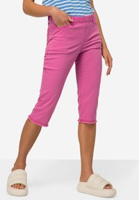 Pantaloni cropped rosa con una comoda cintura elastica, dotati di tasche laterali e dettagli con orlo sfilacciato. Abbinati a calzature bianche da infilare.