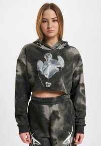 Cropped mikina s čiernym tie-dye vzorom a potlačou anjela spolu s textom "Thug Life". Vyrobená z mäkkého materiálu, s kapucňou na sťahovanie.