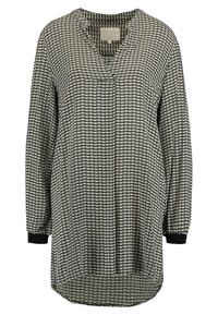 Blusa de mangas longas em padrão houndstooth preto e creme, com decote em V, tecido macio e punhos com acabamento em preto sólido.