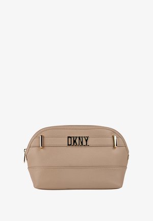 Bolso de cosméticos beige de DKNY con forma redondeada, material texturizado, detalles en hardware dorado y un logo negro prominente en la parte frontal.