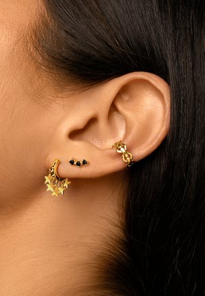 Pendientes de aro dorados con diseño de estrella y luna creciente; tres piedras negras en los aros adyacentes; presentan metal brillante y bordes suaves.