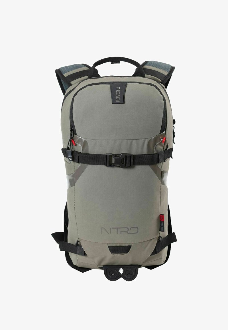 Mochila de tela gris con detalles negros, correas ajustables, cierre de hebilla y logotipo. Presenta un diseño aerodinámico y un bolsillo frontal con cremallera.