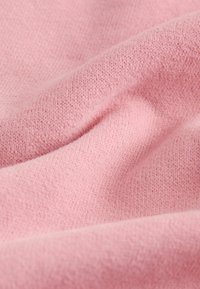 Tissu tricoté rose clair au toucher doux, présentant un motif subtil de points entrelacés, créant de douces ondulations et plis.